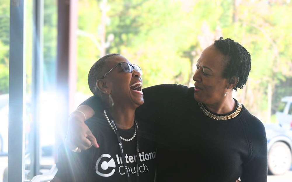 Two women laughing together outside the entrance at Intentional Church in Powder Springs, Georgia