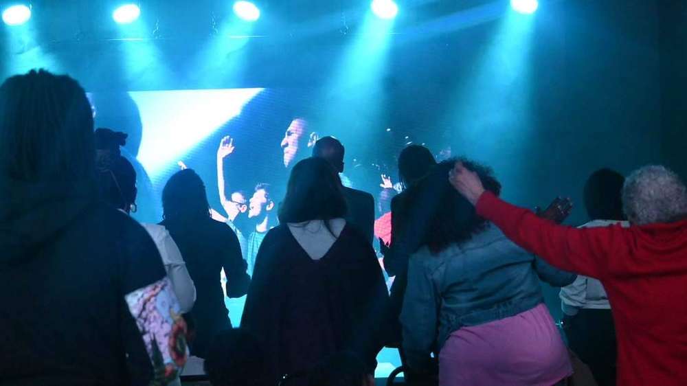 The congregation worshipping with hands raised under stage lights at Intentional Church in Powder Springs, Georgia
