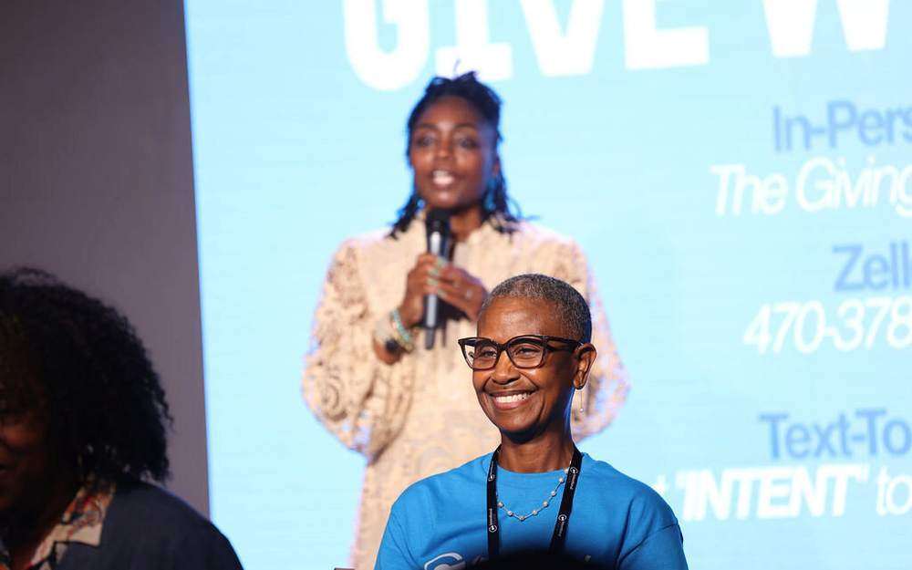 A leader sharing giving information on stage in front of the giving screen at Intentional Church in Powder Springs, Georgia