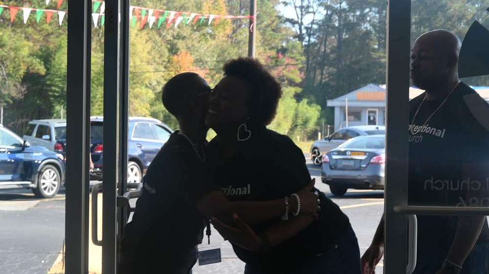 Two people embracing at the glass entrance doors of Intentional Church in Powder Springs, Georgia