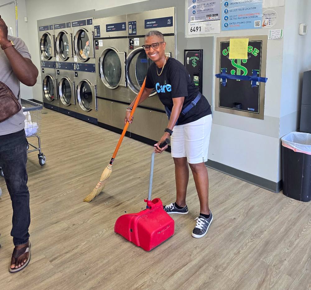 An iCare volunteer from Intentional Church sweeping the laundromat floor during a Laundry Love outreach