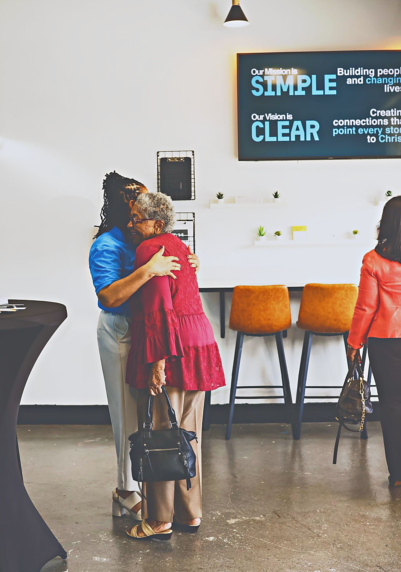 A volunteer in a blue Intentional Church shirt embracing a guest in the welcome area at Intentional Church in Powder Springs, Georgia
