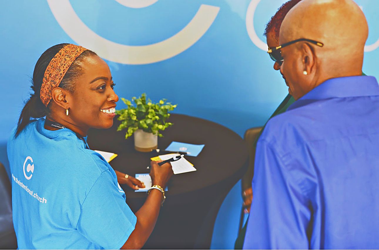 A volunteer at the welcome table helping a guest fill out a connect card at Intentional Church in Powder Springs, Georgia