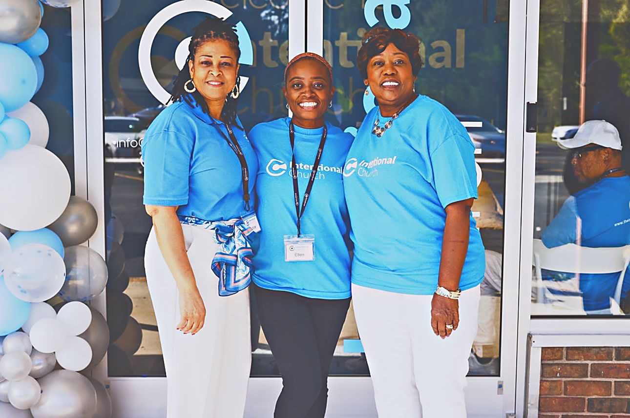 Three volunteers in blue Intentional Church shirts welcoming guests at the entrance in Powder Springs, Georgia