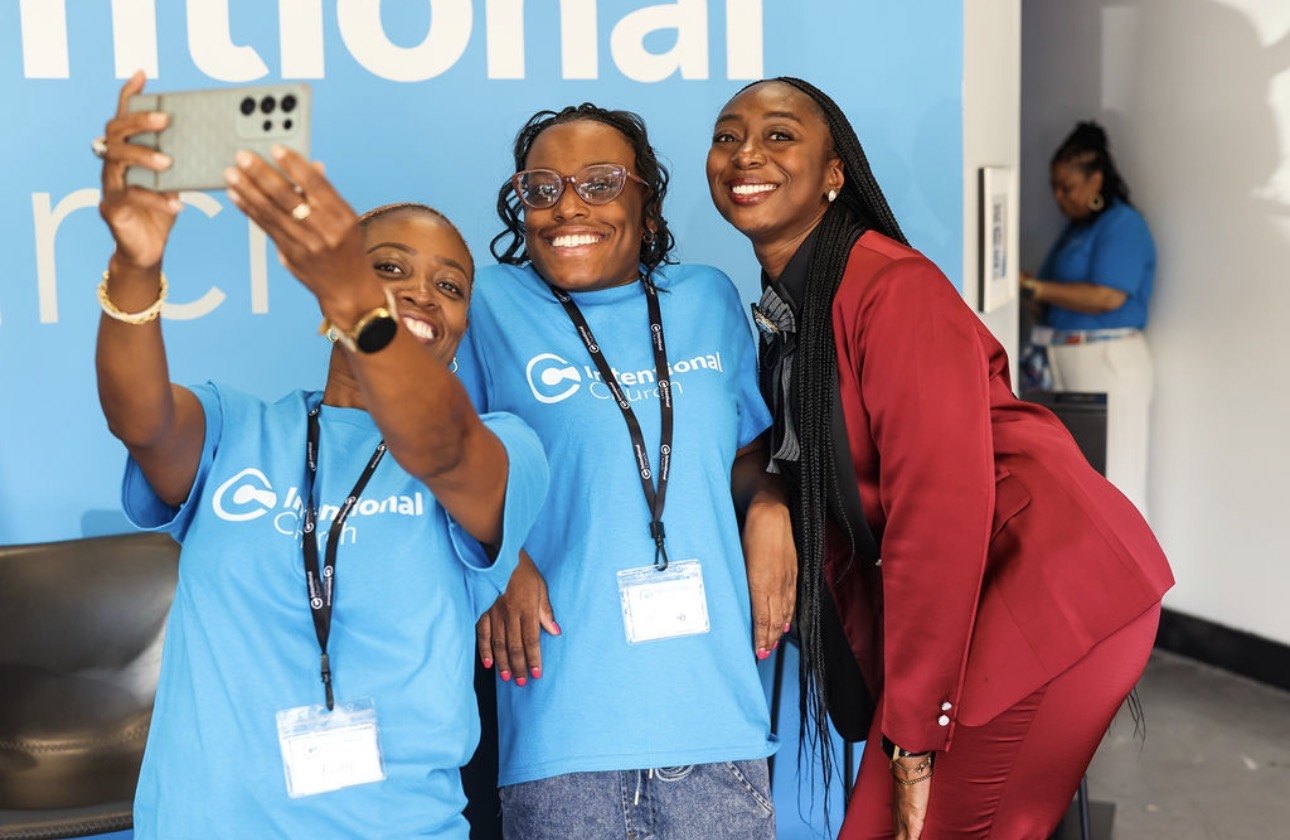 Three volunteers in blue Intentional Church shirts taking a selfie together with a guest in Powder Springs, Georgia