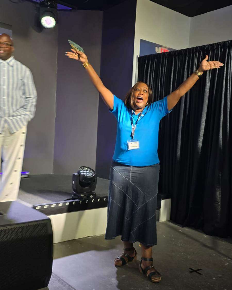A volunteer in an Intentional Church shirt worshipping with arms raised in Powder Springs, Georgia